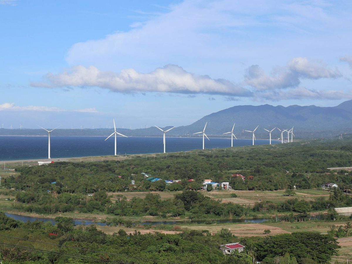 Line of wind turbines along the coast of Bangui, Ilocos Norte, with mountains behind