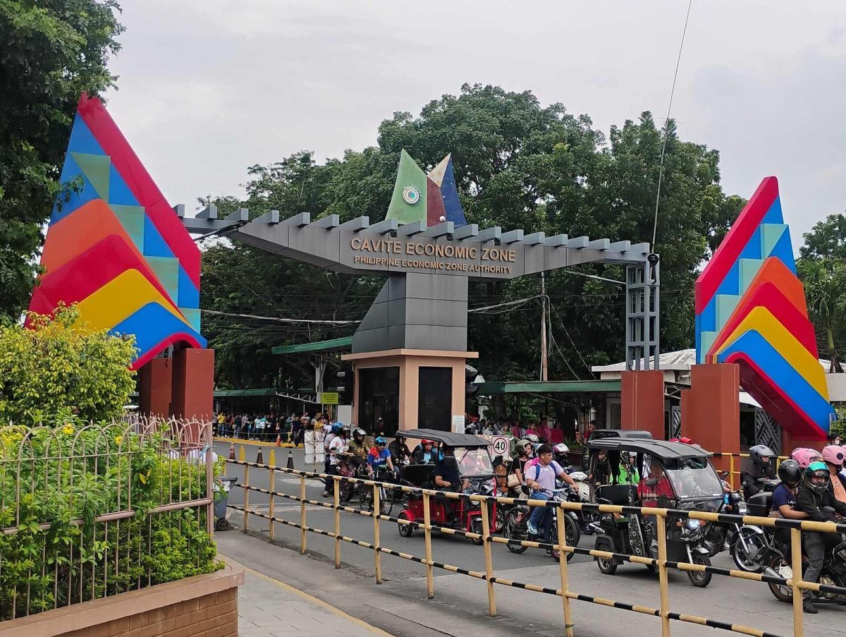 Colorful main gate of the PEZA-run Cavite Economic Zone in Rosario, Cavite, with workers arriving by tricycle