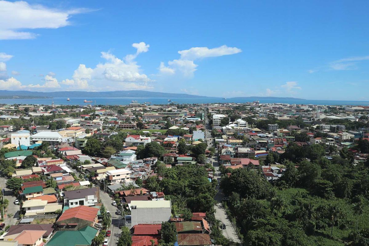 Aerial view of Davao City rooftops and the Davao Gulf under a partly cloudy sky