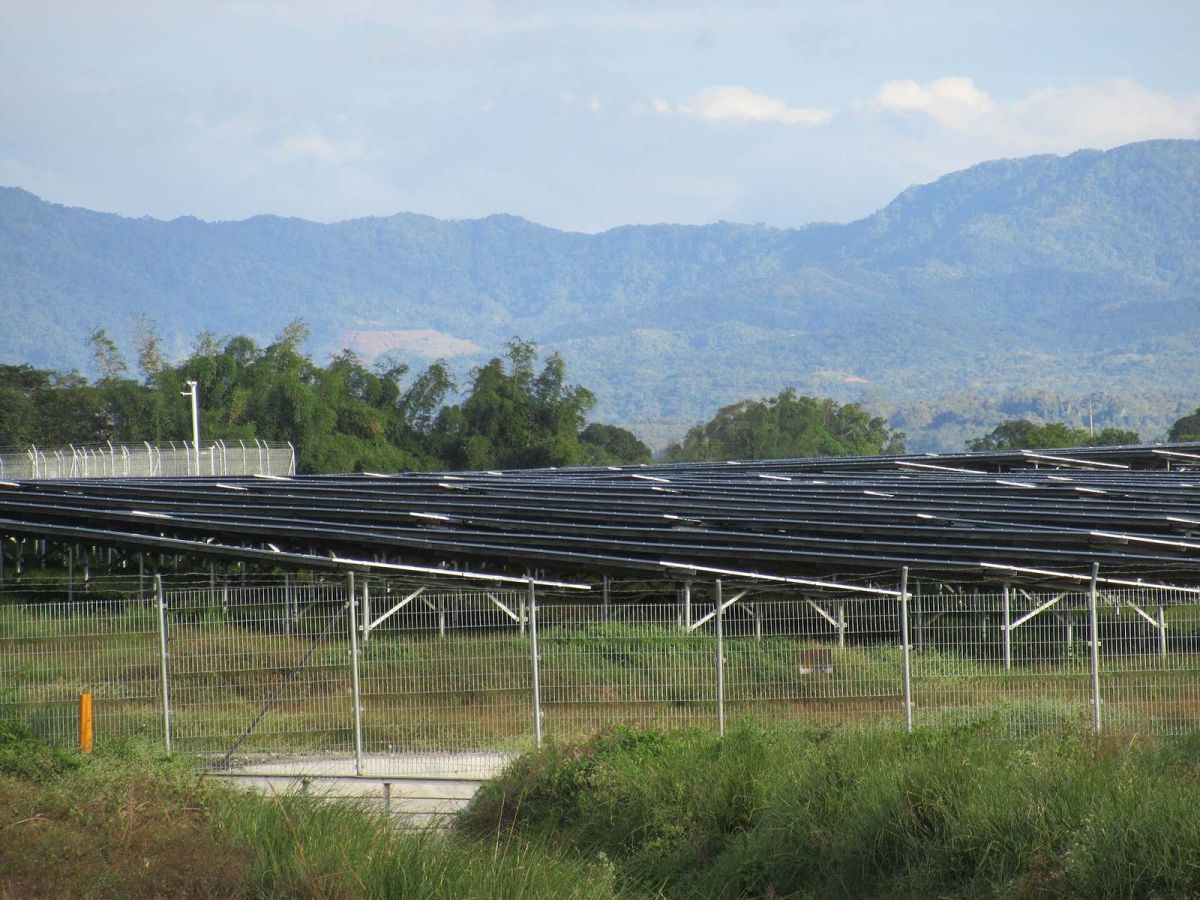 Rows of solar panels at a solar power plant in Bulacan with mountains in the background